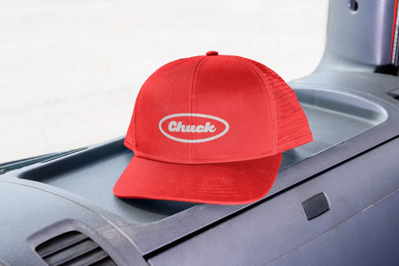 Close-up photo of a red cap with 'Chuck' logo on a vehicle dashboard, symbolising the brand identity for Chuck's junk removal services.